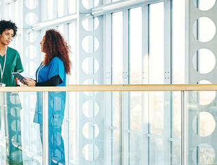 Three diverse medical professionals talking in modern hospital corridor