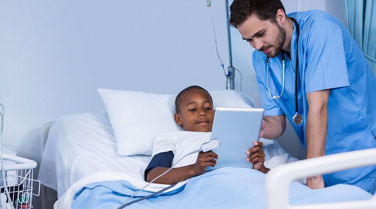 Male nurse and patient using digital tablet in ward