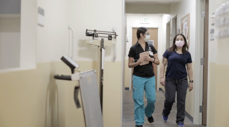 Two nurses walk through hospital hallway